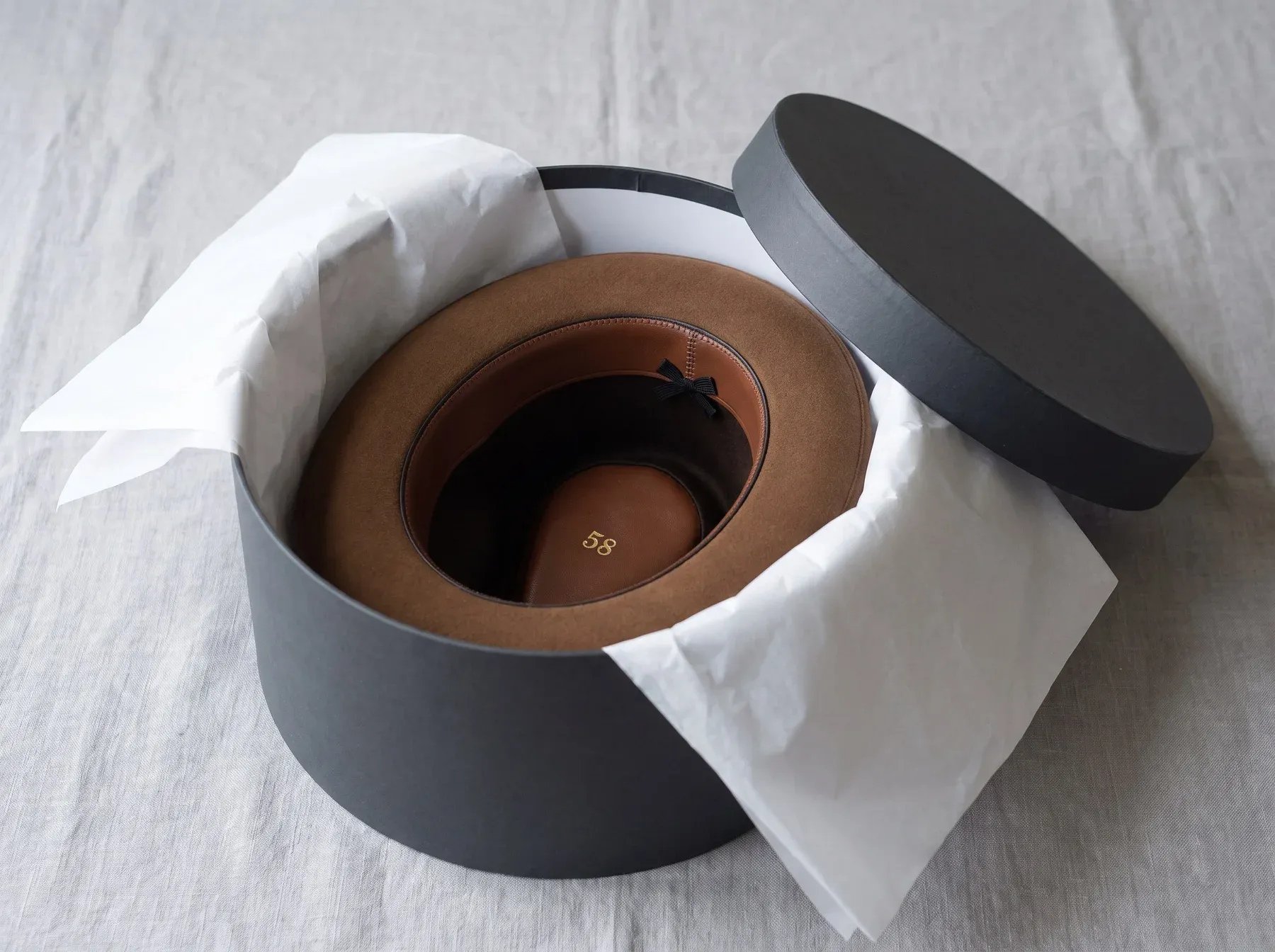 A generated lifestyle photograph for Kwal-ity Hats, Orbit3D's demo brand: a felt fedora resting in an open hatbox.